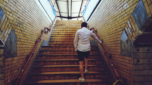 Rear view of man walking on staircase