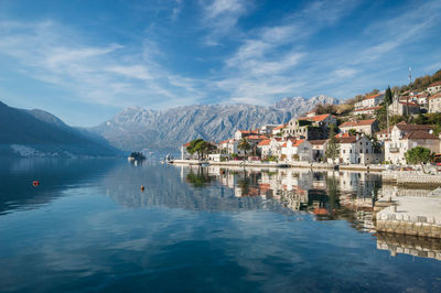 Buildings by lake against sky