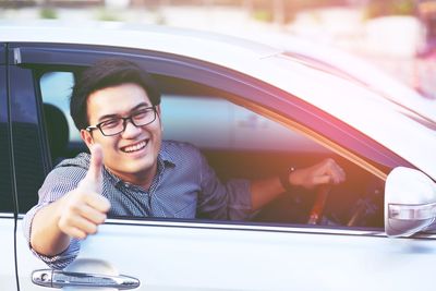 Portrait of smiling man gesturing thumbs up while sitting in car