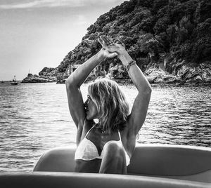 Portrait of woman with arms raised against sea