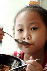 Close-up portrait of girl eating food in bowl at restaurant