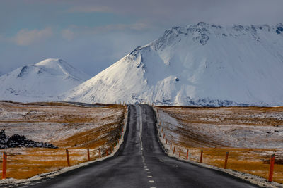 Road amidst snowcapped mountains against sky