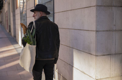 Adult man in hat holding bread and vegetable bag on street. madrid, spain