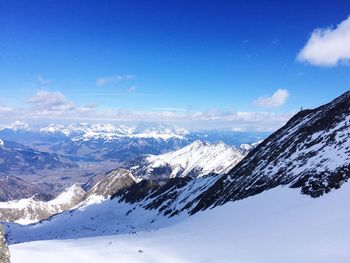 Scenic view of snowcapped mountains against blue sky