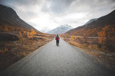 Rear view of man walking on road