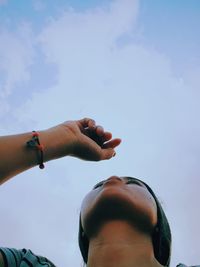 Low angle view of woman  hand against sky