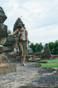 Woman looking down while standing against built structure