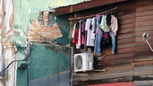 Low angle view of clothes hanging over air container mounted on house wall