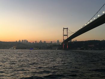 Silhouette bridge over river against sky during sunset