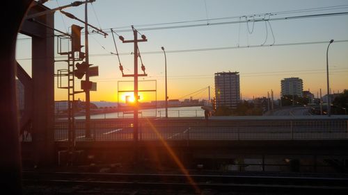 Railroad tracks in city against sky during sunset