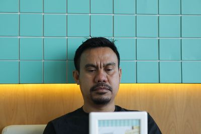 Man looking at picture frame against tiled wall