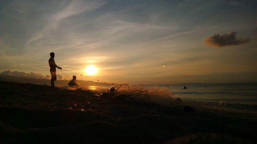 Silhouette man on beach against sky during sunset