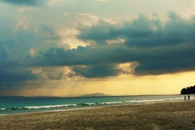 Scenic view of beach against cloudy sky