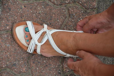Cropped image of woman adjusting sandal on footpath