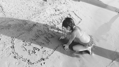 High angle view of girl drawing on wet sand at beach