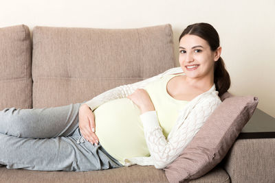 Portrait of smiling young woman sitting on sofa