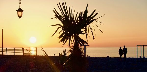 Silhouette people on beach against sky during sunset