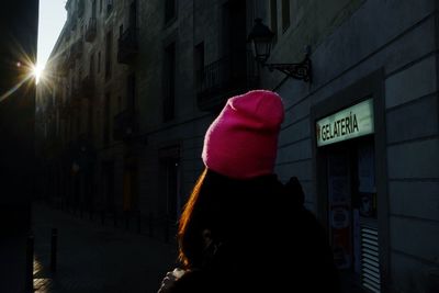 Rear view of woman standing on street against illuminated buildings in city