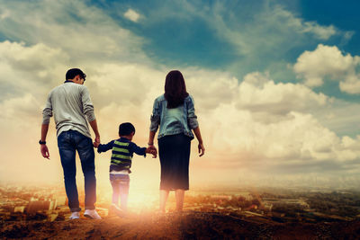 Rear view of friends standing against sky during sunset