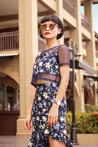 Portrait of young woman wearing sunglasses while standing outdoors