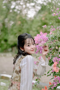 Portrait of young woman standing against trees