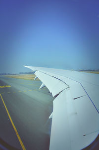 Close-up of airplane wing against clear blue sky