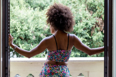 Rear view of woman looking through window