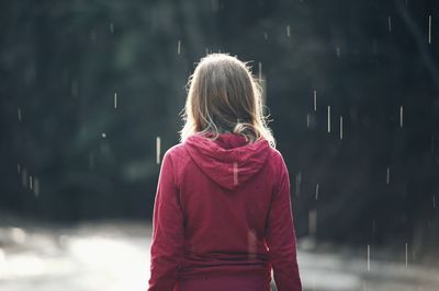 Rear view of girl standing in rain