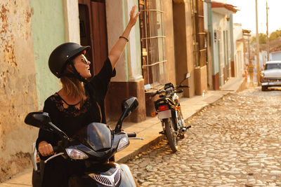 Side view of man riding motor scooter on street