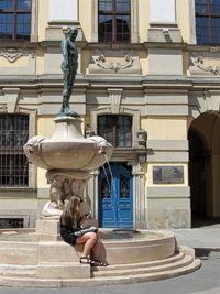 Statue of woman sitting outside building