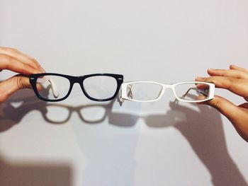 Close-up of hand choosing between two glasses over white background