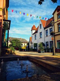 Buildings by canal against sky in city