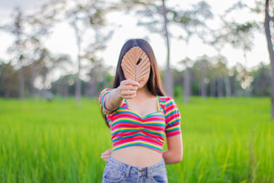 Woman holding leaf while standing on land