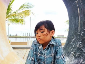 Portrait of boy looking away while standing on palm trees