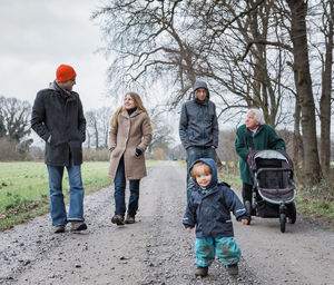 Full length of family walking on dirt road during winter