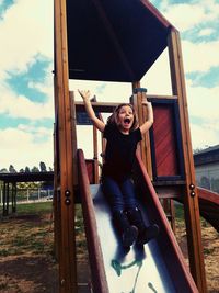 Full length of girl screaming on slide at playground