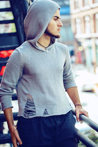 Young man looking away while standing by railing