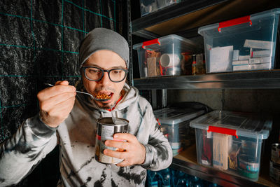 Man eating canned food in undeground emergency shelter