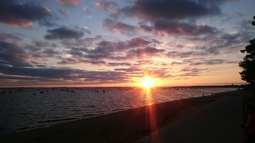 Scenic view of sea against cloudy sky at sunset