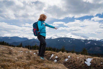 Rear view of man standing on mountain against sky