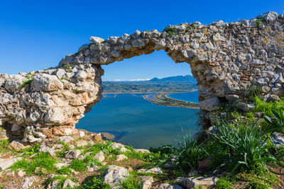 Rock formations by sea against clear blue sky