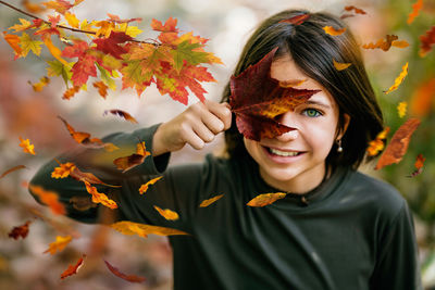 Portrait of cute girl holding autumn leaf outdoors