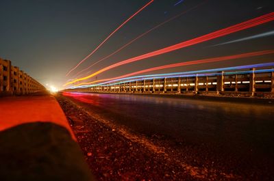 Light trails on road against sky at night