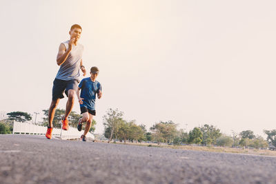 Rear view of boy running on road against sky