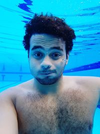 Portrait of shirtless young man swimming in pool