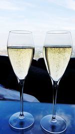 Close-up of champagne flutes on table against sky