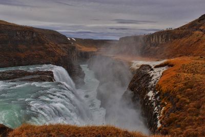 Scenic view of waterfall by sea against sky