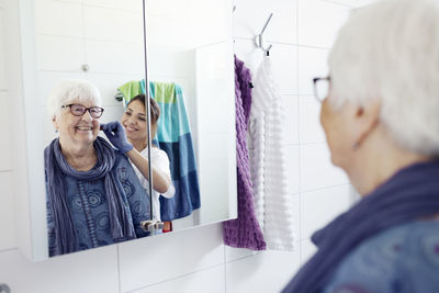 Nurse combing woman's hair in bathroom