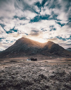 Scenic view of arid landscape against cloudy sky