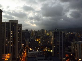 Illuminated cityscape against cloudy sky